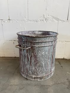 an old metal bucket sitting in front of a white wall