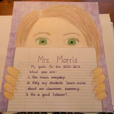 a child's hand holding up a piece of paper with the words mrs marris written on it