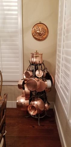 a stack of copper pots sitting on top of a wooden floor next to a window