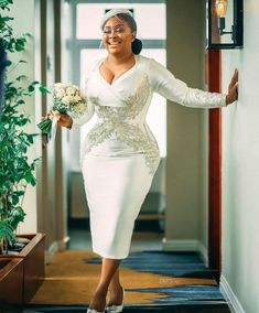 a woman in a white dress is walking down the hallway with her arms out and smiling