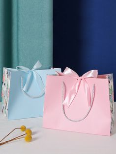 two bags with bows on them sitting next to each other, one pink and one blue