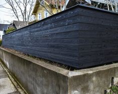 a wooden structure sitting on top of a cement wall next to a tree filled street