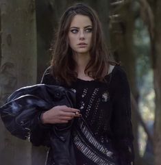 a young woman is standing in the woods with her hand on her hip and looking at the camera