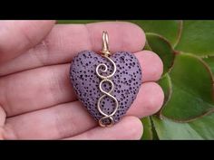 a person holding a purple heart shaped pendant