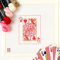 cross - stitch cards, yarn and crochet scissors on a table