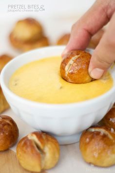 a person dipping something in a bowl with croissants around it