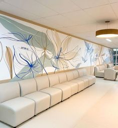 an empty waiting room with white couches and blue flowers painted on the wall behind them