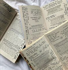 four open books with writing on them sitting on a bed