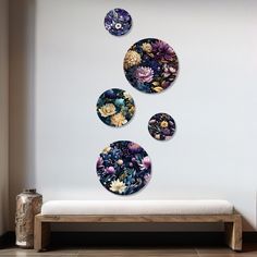 three plates are hanging on the wall next to a wooden bench and vase with flowers in it