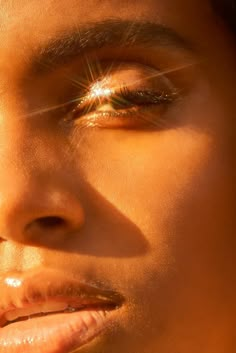 a close up of a woman's face with sun shining through her eyes