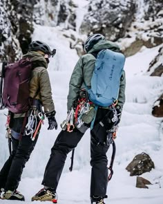 two people with backpacks and snowshoes standing in front of a frozen waterfall