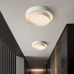 two circular lights are hanging from the ceiling in an empty hallway with black and white striped walls