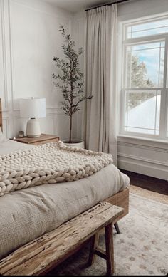 a bedroom with a large bed and a tree in the corner on one side of the bed