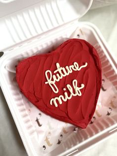 a red heart shaped cake with the words future milk on it sitting in a plastic container