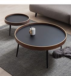 two coffee tables sitting on top of a gray rug next to a couch and chair