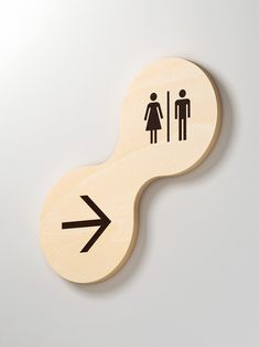 a wooden sign with an arrow pointing to the man and woman bathroom symbol on it