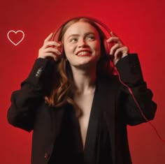 a woman listening to headphones with a heart drawn on the wall in the background