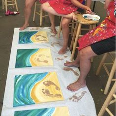 three people sitting at tables with paintings on them