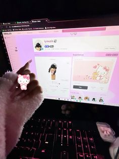 someone is holding a hello kitty sticker in front of a computer screen with the keyboard and mouse