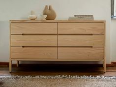 a dresser with two vases on top of it and a rug in front of it