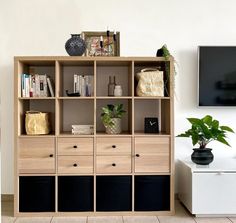 a living room with an entertainment center and plant on the side table in front of it