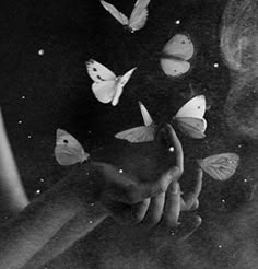 black and white photograph of butterflies flying in the air over a woman's face