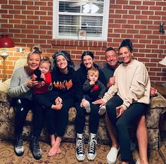 a group of people sitting on top of a couch in front of a brick wall