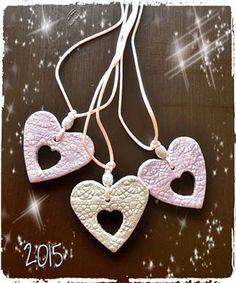 three hearts are hanging from a string on a wooden surface with sparkles in the background