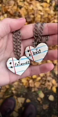 two heart shaped pendants with the words best friends hanging from them on a person's hand