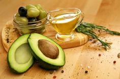 an avocado cut in half on a cutting board with olives and oil