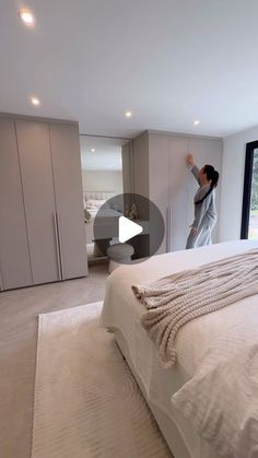 a woman standing in the middle of a bedroom next to a bed and closets