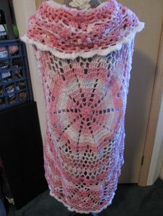 a crocheted pink and white vase sitting on top of a black table next to a door