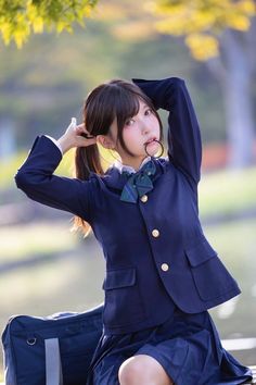 a young woman sitting on top of a bench wearing a blue suit and green bow tie