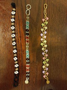 three beaded bracelets sitting on top of a wooden table next to each other