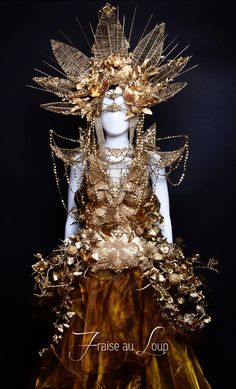 a mannequin dressed in gold and brown with lots of jewels on her head