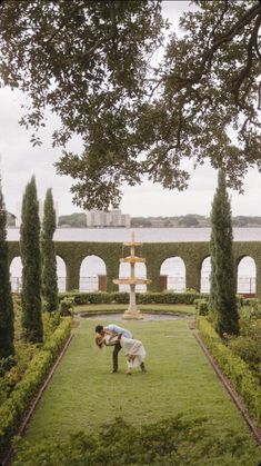 two people kneeling down in the middle of a lush green field with trees and bushes