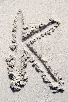 the letter k is drawn in the sand with an arrow on it's side