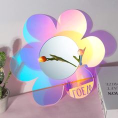 a flower shaped mirror sitting on top of a table next to a potted plant