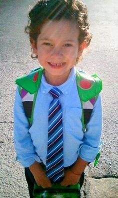 a young boy wearing a blue shirt, tie and suspenders standing in the street