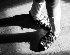 black and white photograph of woman's legs wearing high heels with laces on them