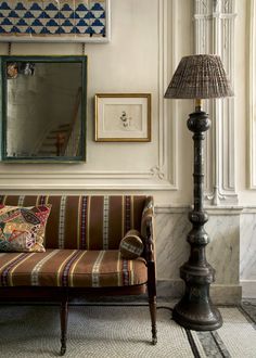 a living room with a couch, lamp and pictures on the wall above it's doorway