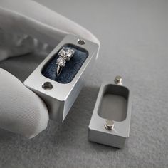 a ring in a box on the floor next to a white glove and napkin holder