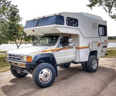 an rv parked on the side of a road next to a tree and water area