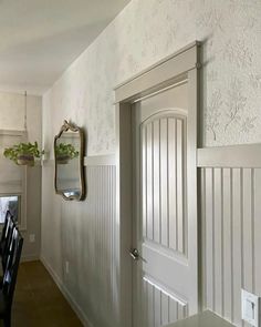 a dining room table and chairs in front of a mirror on the wall next to a door