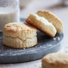 two biscuits sitting on top of a plate next to a glass of milk