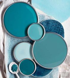 three pans with blue paint sitting on top of each other next to a brush