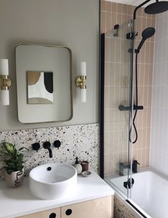 a white sink sitting under a bathroom mirror next to a bath tub and shower head