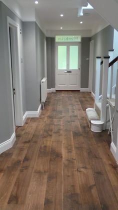 an empty hallway with wood floors and white trim