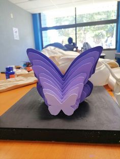 a purple butterfly sculpture sitting on top of a wooden table