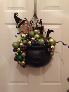 a black pot filled with lots of ornaments hanging from the side of a white door